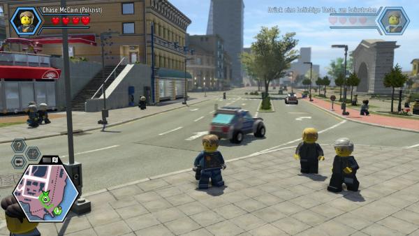 Screenshot: Chase steht am Gehsteig und im Hintergrund sind eine Straße, Autos, Passanten und Gebäude