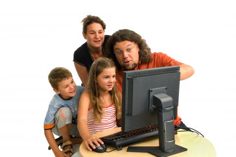 Eltern und zwei Kinder vor einem Bildschirm